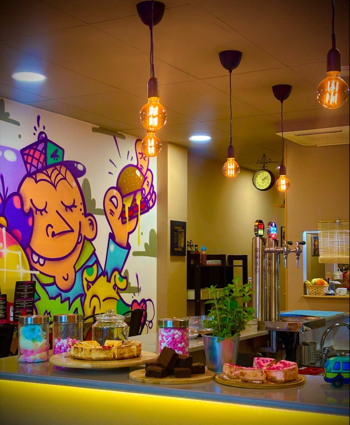 La barra con el mural y los postres
